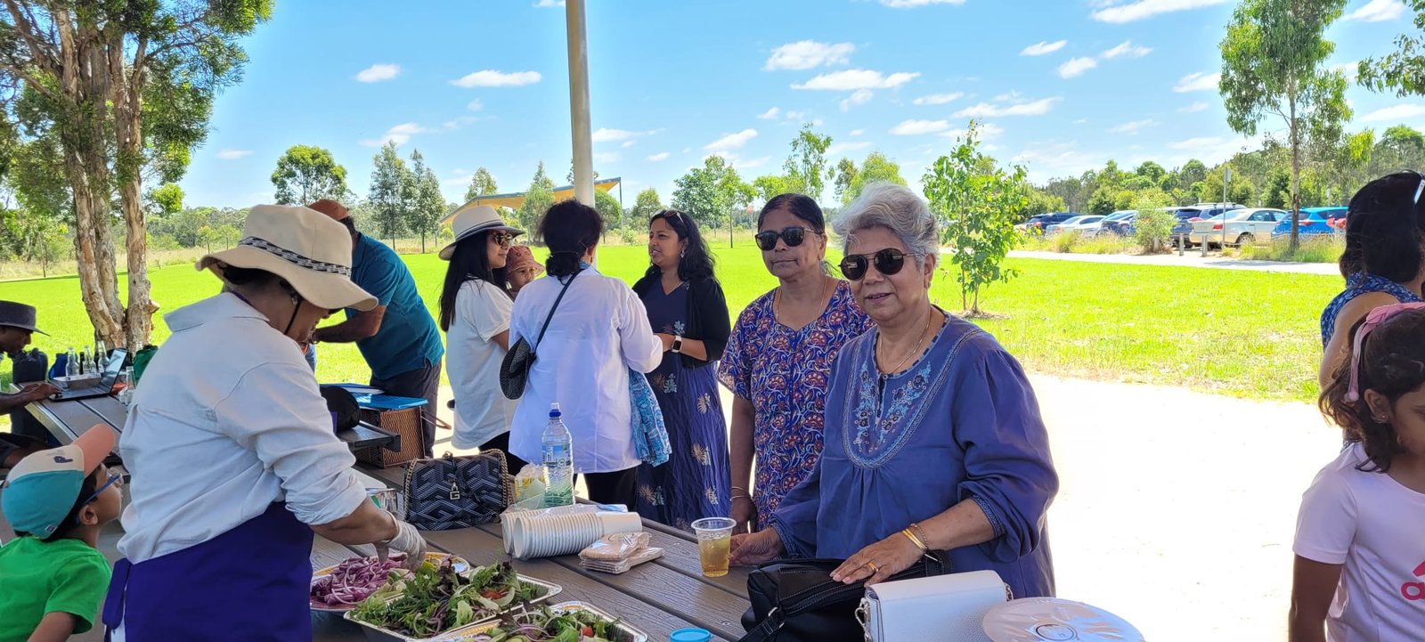 About Us Alumni and families sharing food at a picnic
